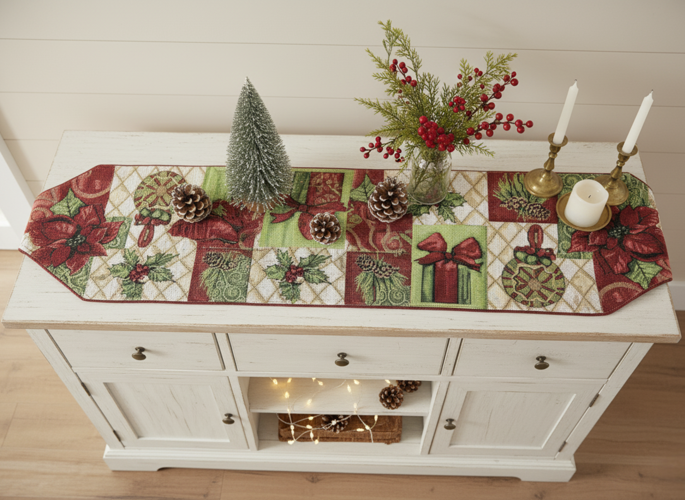 Decorative Christmas table runner on a white cabinet with festive decorations.