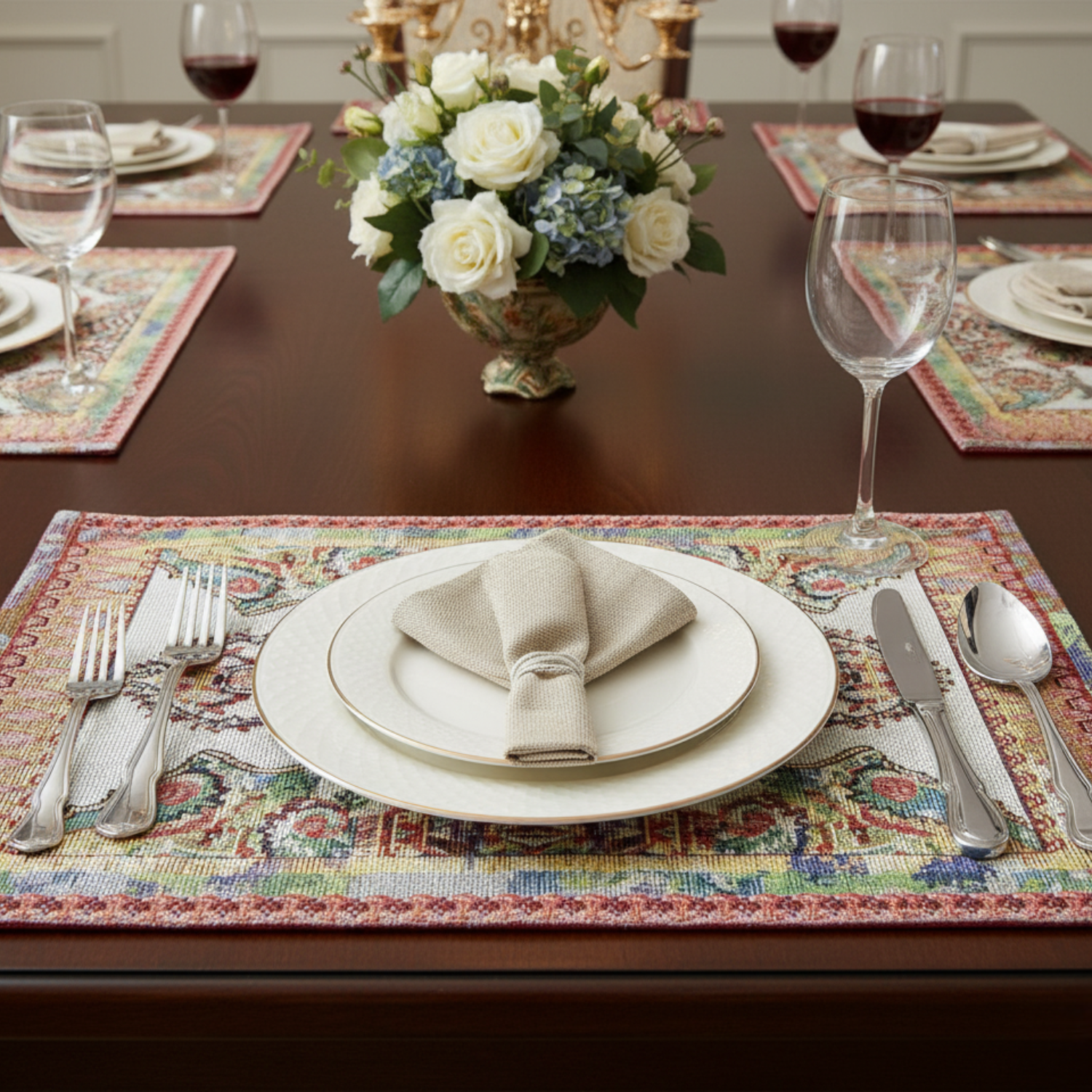 Dining table set with place settings, cutlery, and a floral centerpiece and paisley placemats.