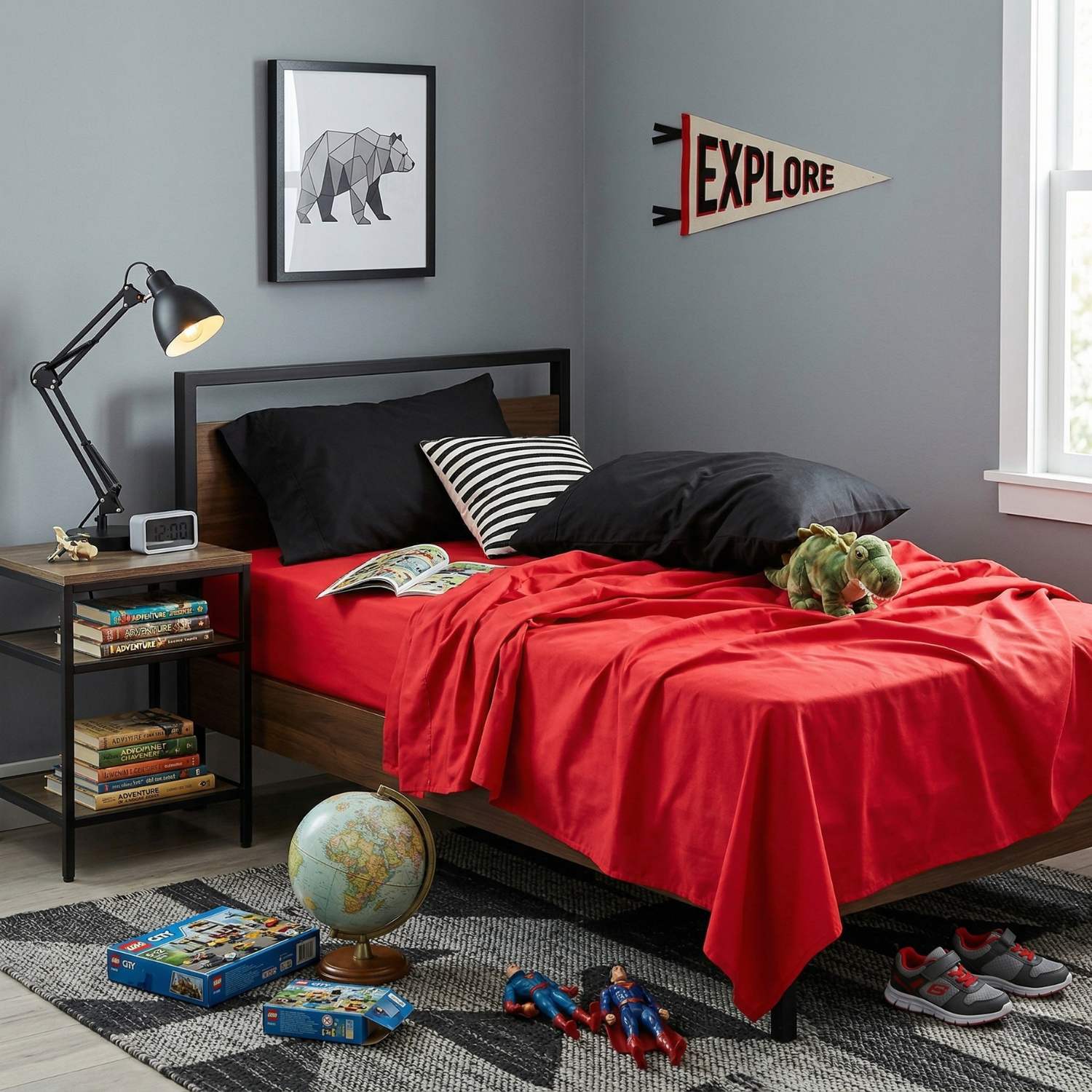 Vibrant red 100% cotton bed sheets and black pillowcases on a child's bed, surrounded by toys, a globe, and an explore pennant on a gray wall.