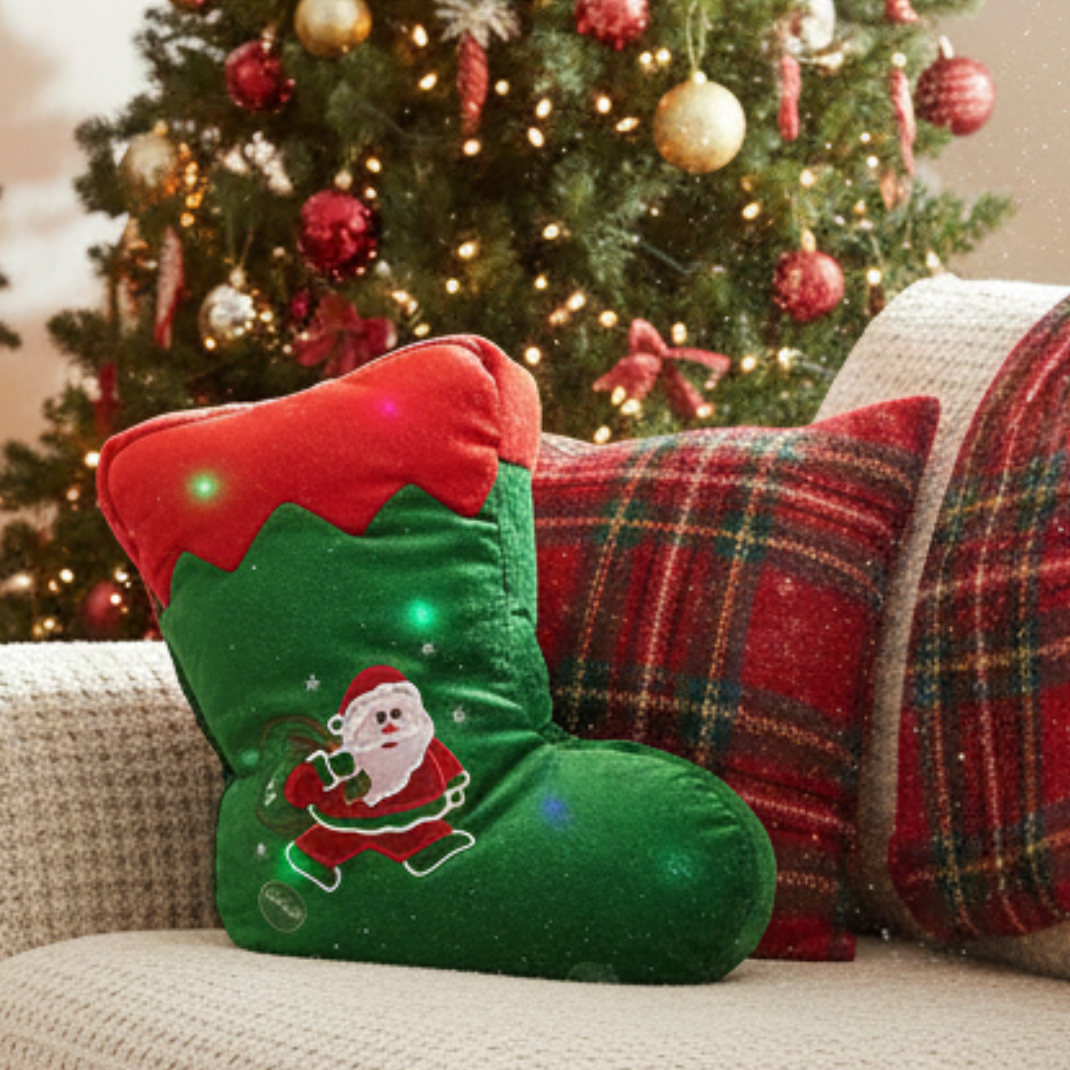 Green and red Christmas stocking with Santa Claus design on a couch in front of a decorated tree.