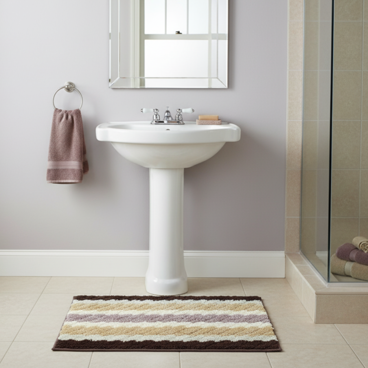 Bathroom with a pedestal sink, striped camel brown, beige, and purple rug, and towel.