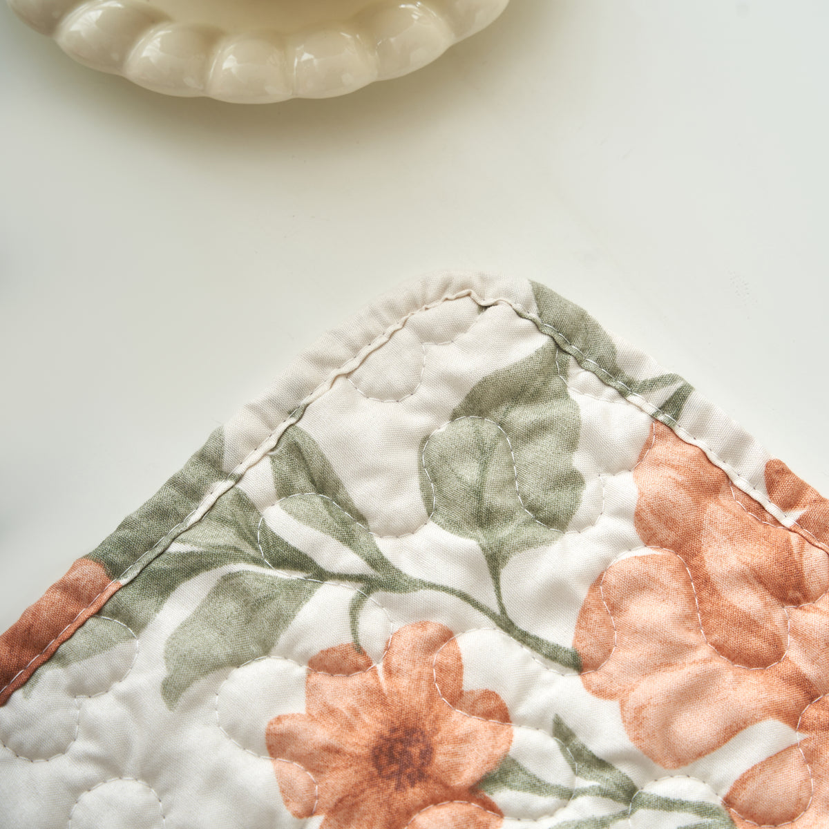 Terracotta rose floral quilted placemat set on a rustic wood dining table