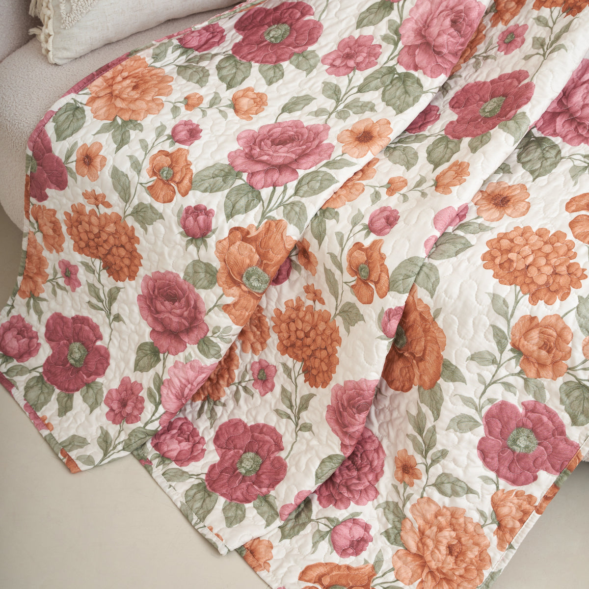 Tache terracotta rose floral quilted throw blanket draped over the arm of a sofa