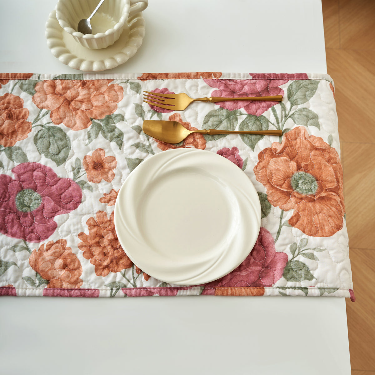Tache Terracotta Rose Garden quilted table runner laid across a wood dining table