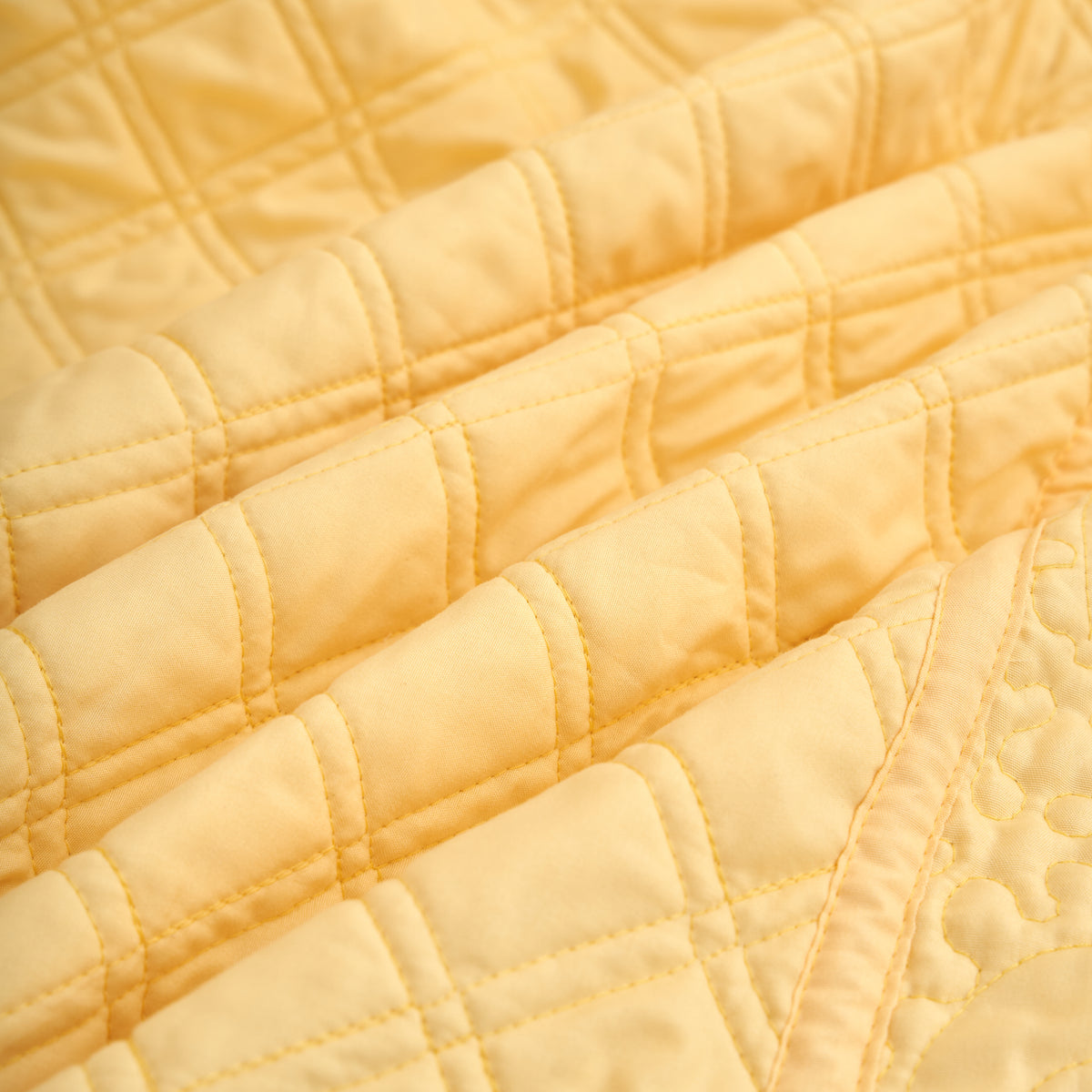 Folded yellow quilted throw blanket showing raised diamond stitch texture and even polyester fill