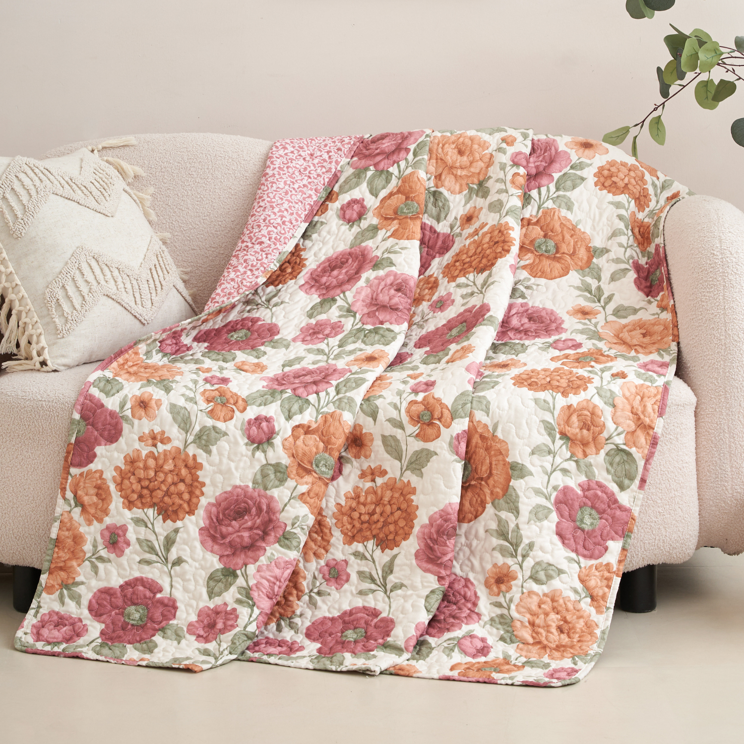 Pink and orange terracotta floral quilted throw blanket in a cozy living room setting