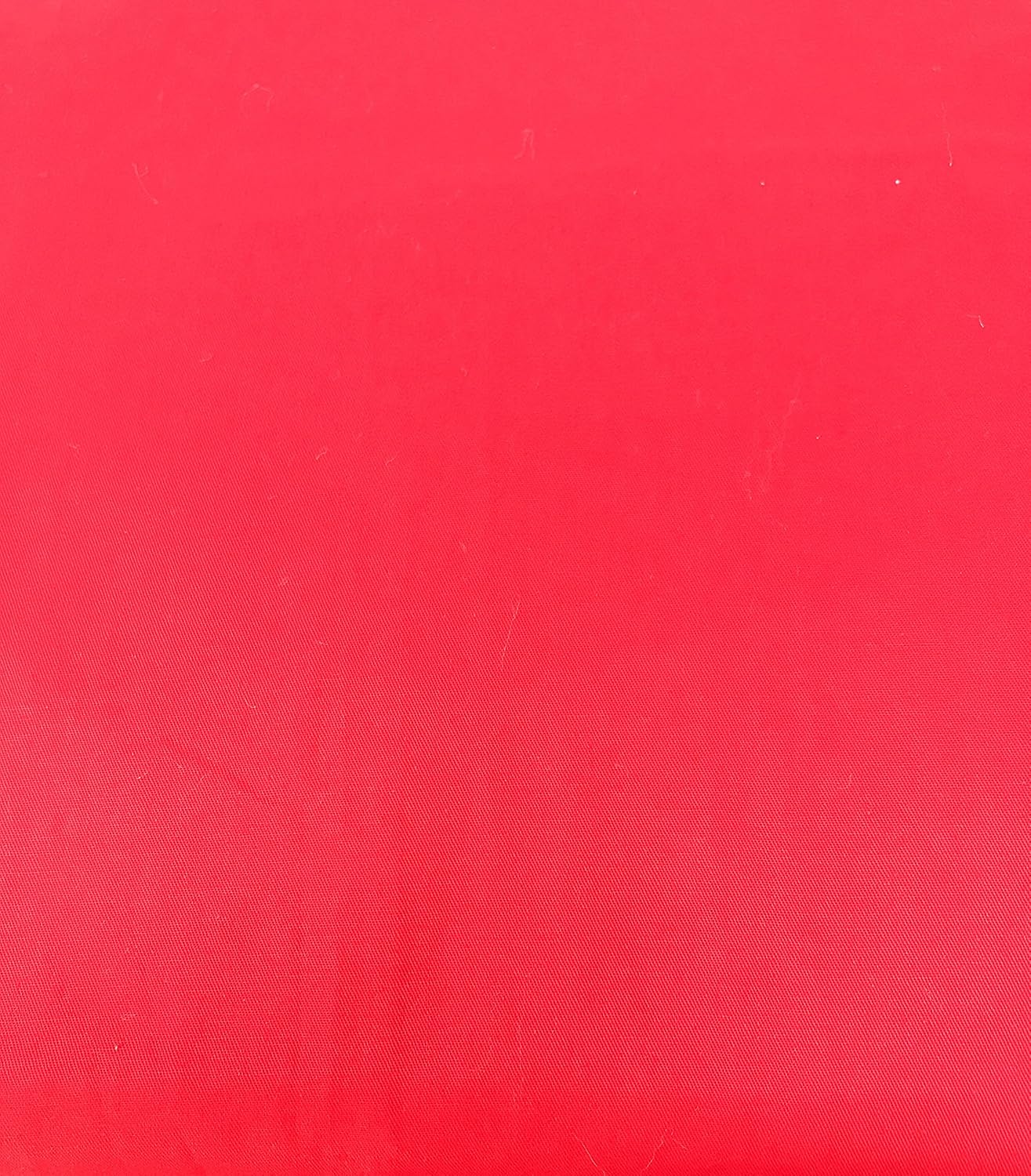 Close up of breathable red cotton bed sheets and black pillowcases.