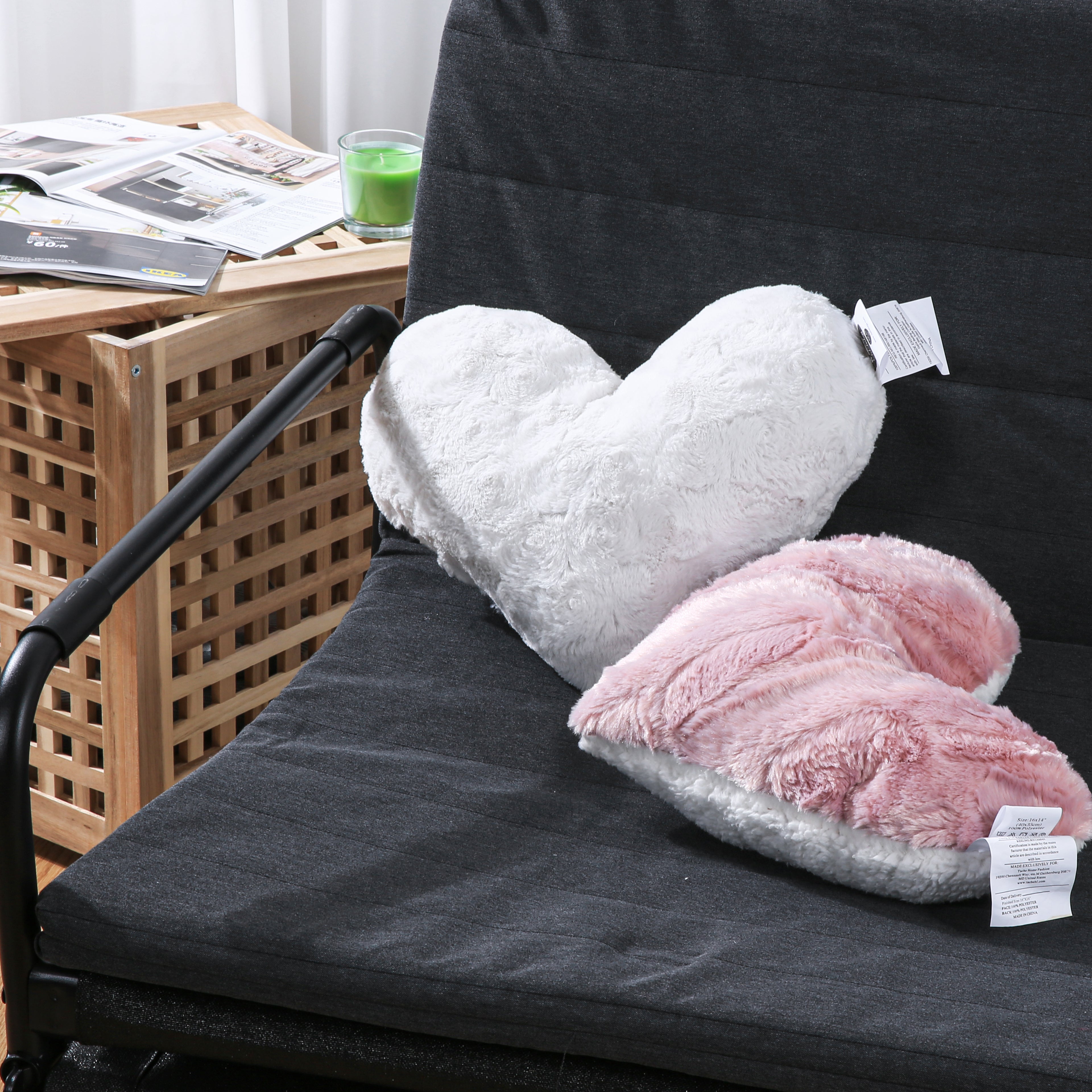 Two faux fur and sherpa heart-shaped pillows sitting on a couch. One is blush dusty rose pink and one is white.