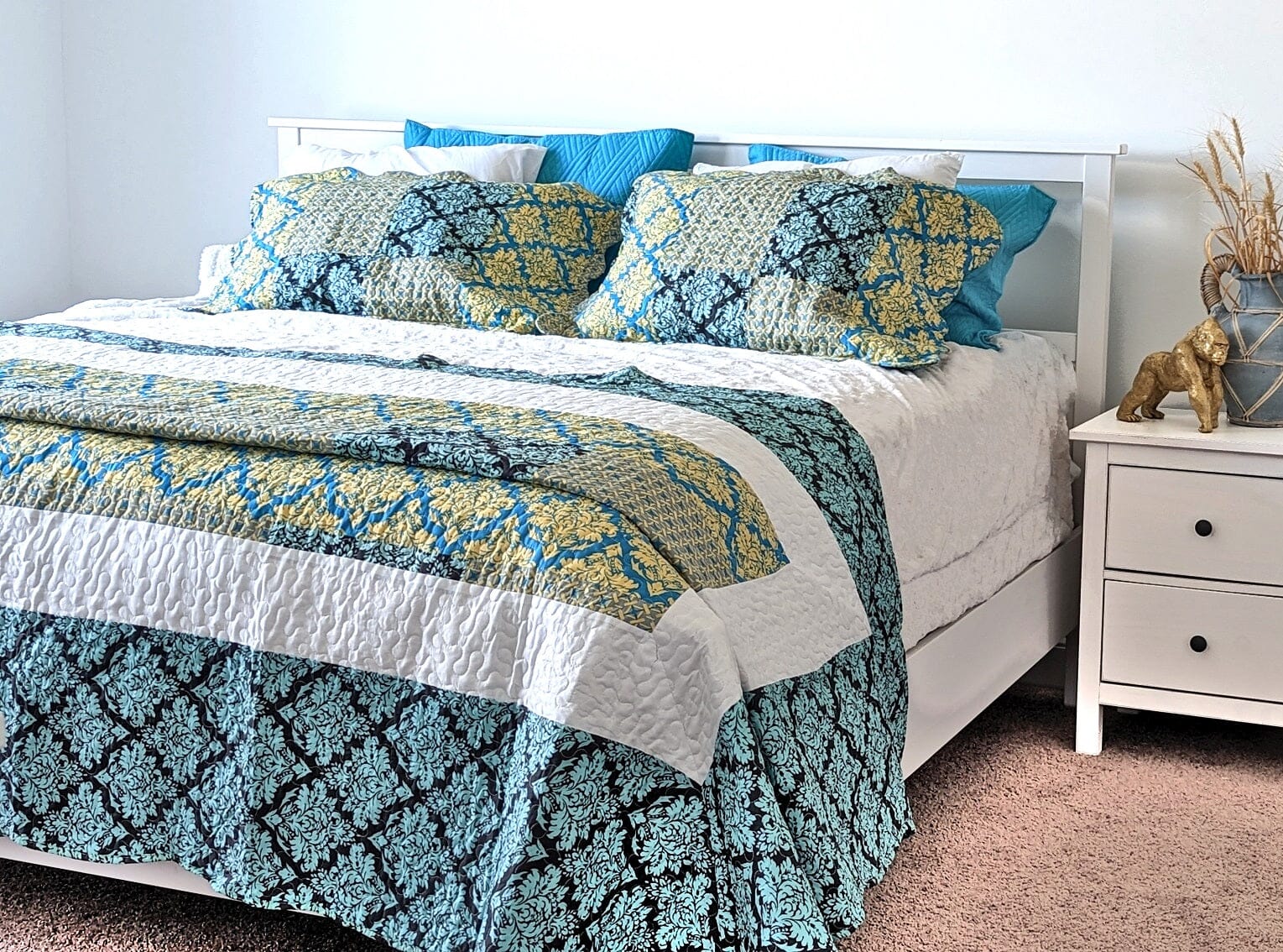 A quilt set with a damask pattern in teal, turquoise, and blue. The quilt is made of 100% polyester and has a scalloped edge. The set includes a quilt, two shams, and a bed skirt. The quilt is machine-washable and tumble-dryable.  The quilt set would be a great addition to any bedroom. The damask pattern is elegant and sophisticated, while the teal, turquoise, and blue colors are vibrant and inviting. The quilt set is also comfortable and cozy, making it perfect for a good night's sleep.