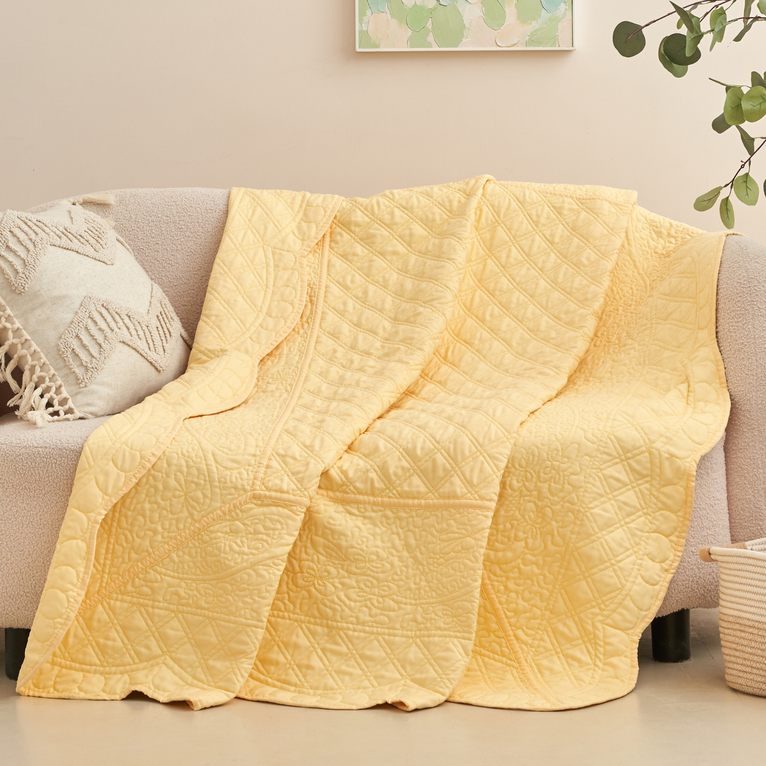 Light buttercup yellow quilted throw blanket with scalloped edge draped over a cream sofa in a boho living room