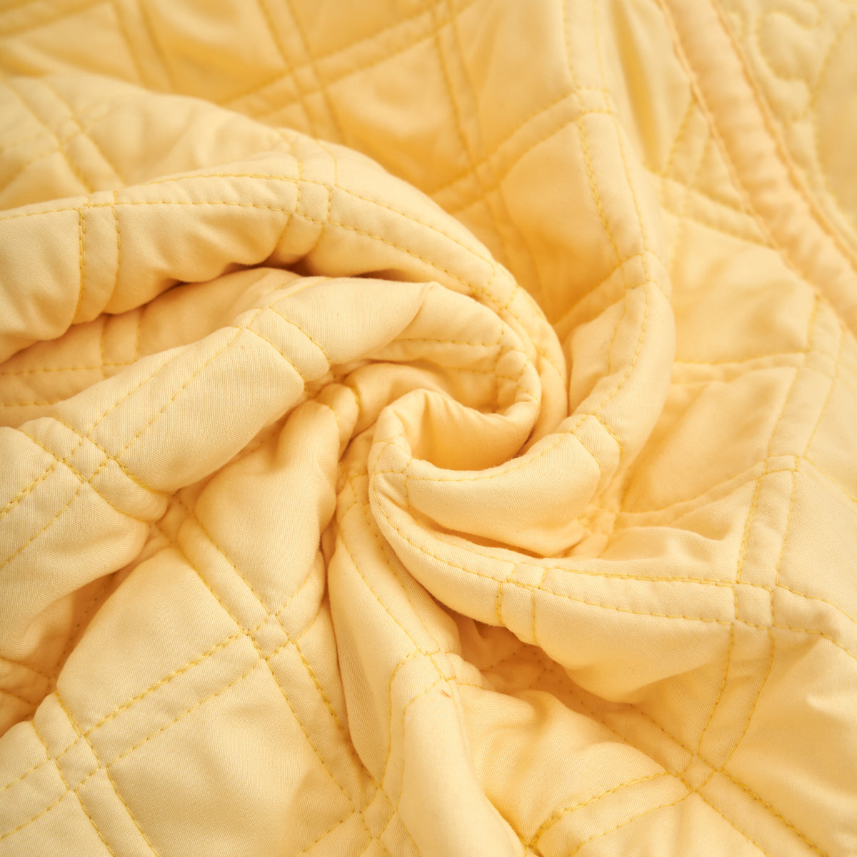 Soft microfiber buttercup yellow quilted throw blanket twisted to show its lightweight drape