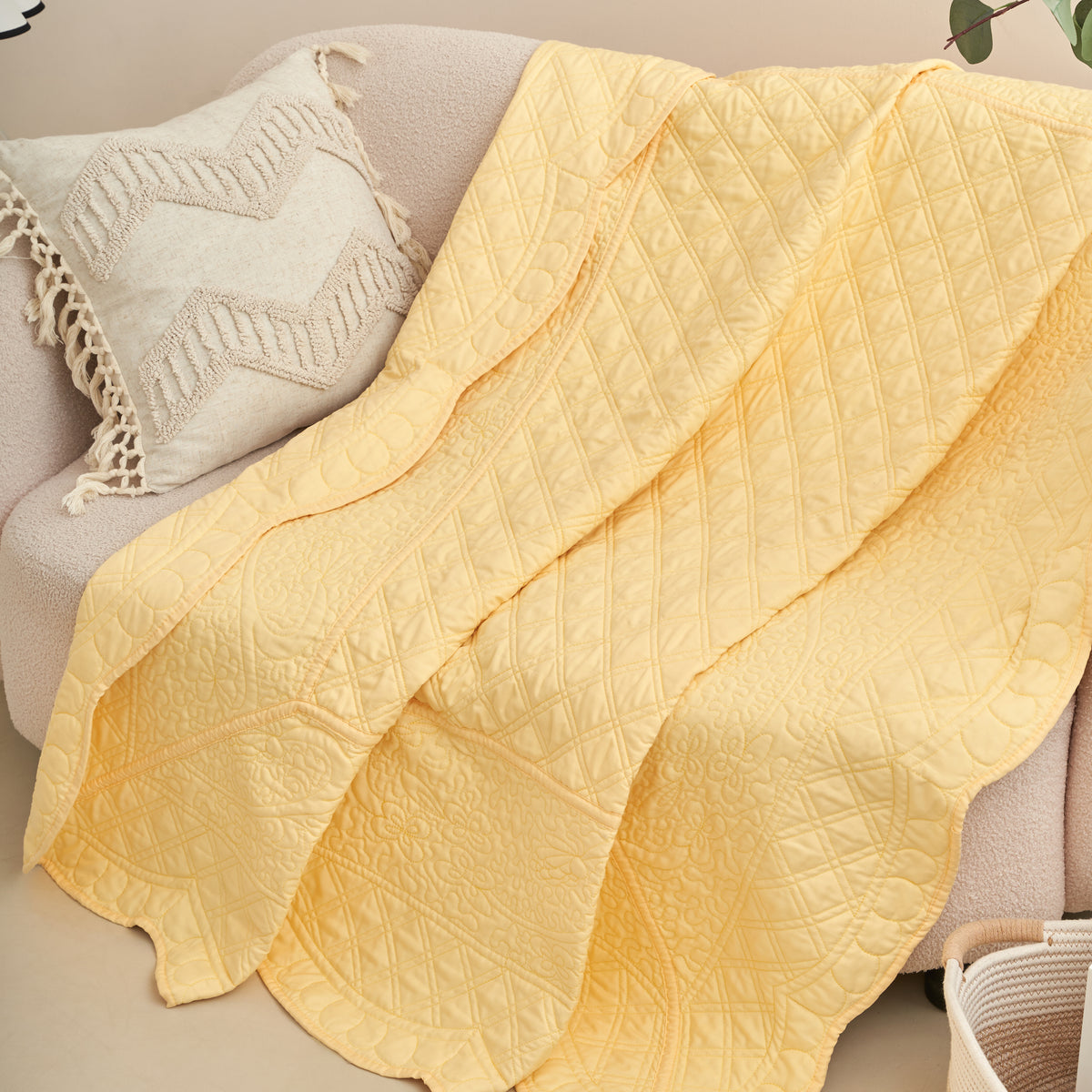 Buttercup yellow scalloped quilted throw draped over a sofa with a boho tasseled accent pillow
