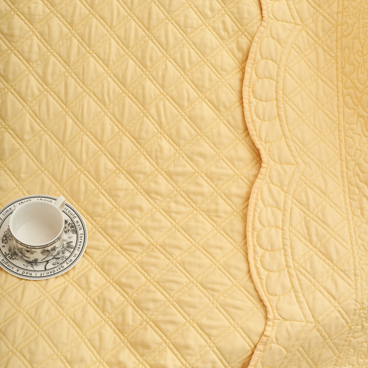 Close-up of diamond crosshatch quilting and scalloped edge on a 50x60 yellow throw blanket